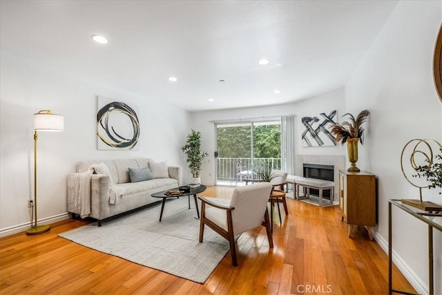 living room featuring a tiled fireplace and light hardwood / wood-style floors