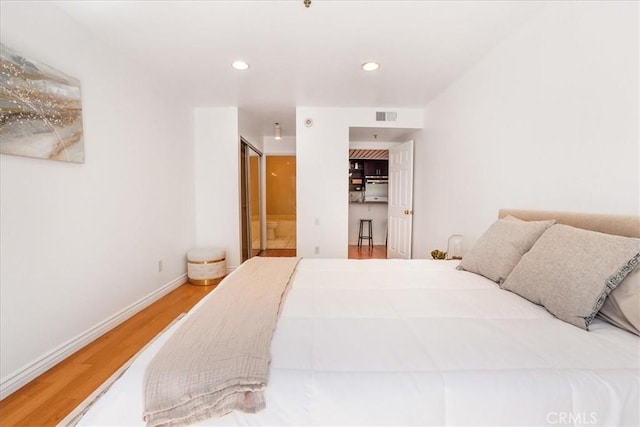 bedroom featuring hardwood / wood-style flooring and ensuite bath