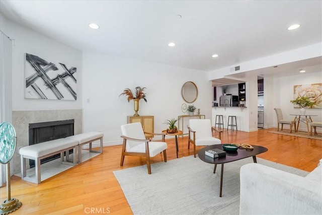 living room with wood-type flooring and a high end fireplace