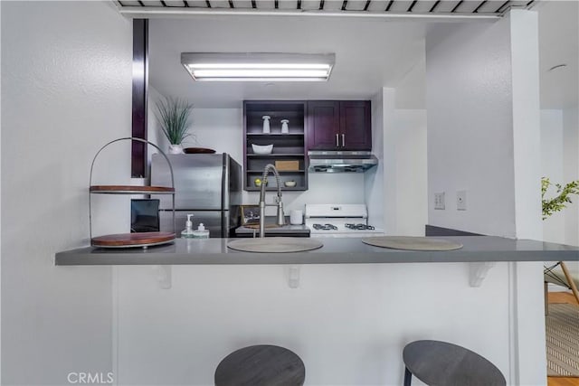 kitchen featuring stainless steel fridge, kitchen peninsula, a breakfast bar area, and stove