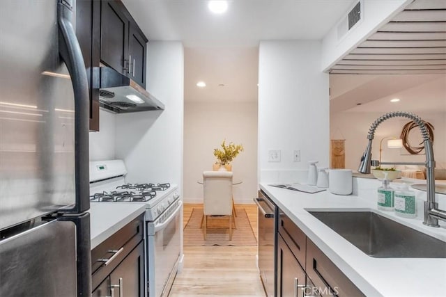 kitchen with stainless steel appliances, light hardwood / wood-style floors, and sink