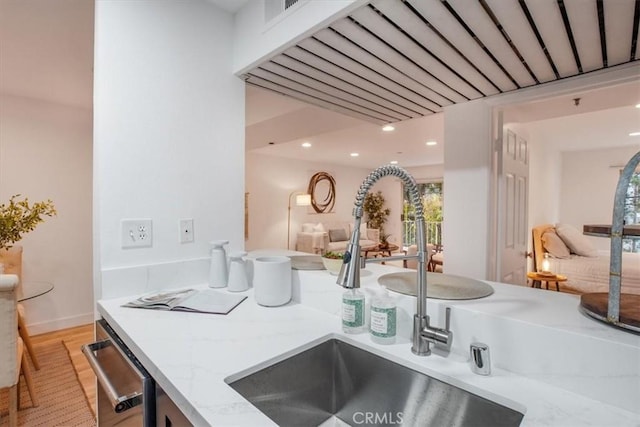 kitchen with light stone countertops, stainless steel dishwasher, and sink