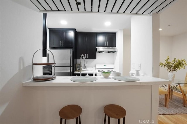 kitchen with sink, range, stainless steel fridge, a kitchen breakfast bar, and kitchen peninsula