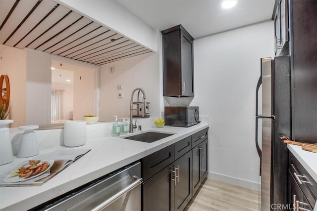 kitchen with sink, dishwasher, dark brown cabinetry, light hardwood / wood-style floors, and light stone countertops