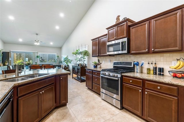 kitchen featuring sink, ceiling fan, appliances with stainless steel finishes, backsplash, and light stone counters