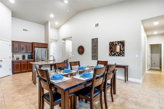 dining room featuring sink, light tile patterned floors, and high vaulted ceiling