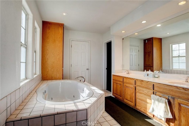 bathroom with a relaxing tiled tub, tile patterned floors, and vanity