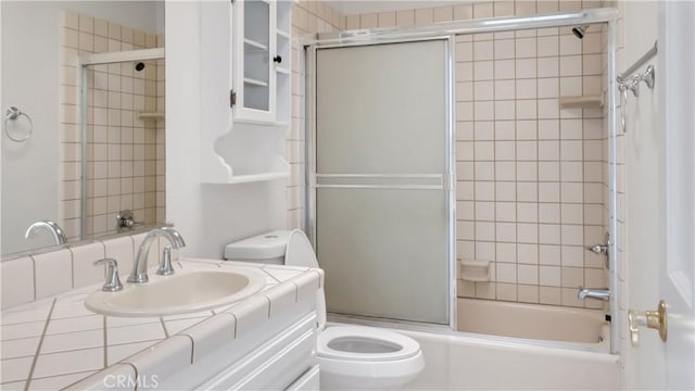 full bathroom with vanity, bath / shower combo with glass door, and toilet