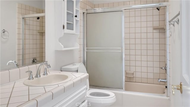 bathroom with toilet, vanity, and bath / shower combo with glass door