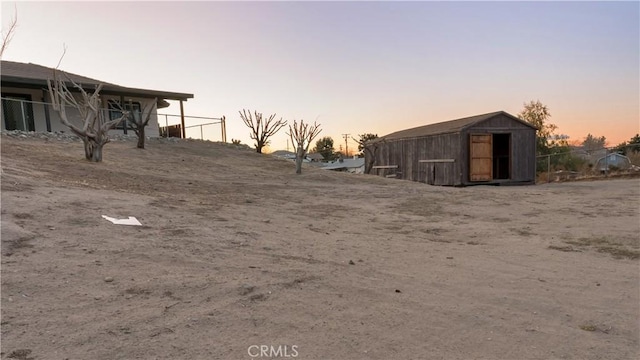 yard at dusk with a storage shed and an outbuilding