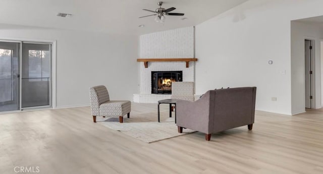 living room featuring ceiling fan, a fireplace, and light hardwood / wood-style floors