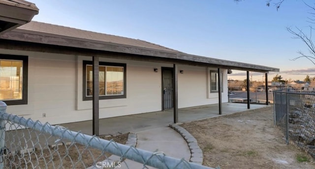 back of property at dusk with a patio area and fence