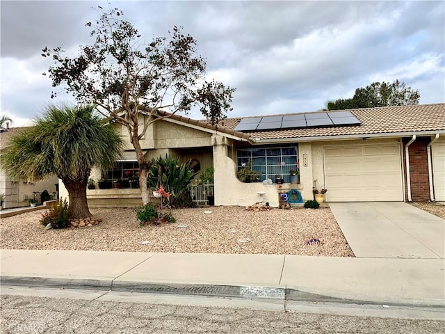 ranch-style home featuring a garage and solar panels