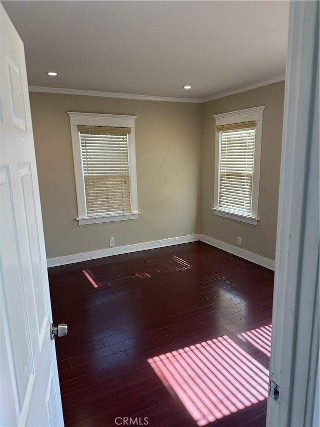 empty room with dark hardwood / wood-style flooring and crown molding