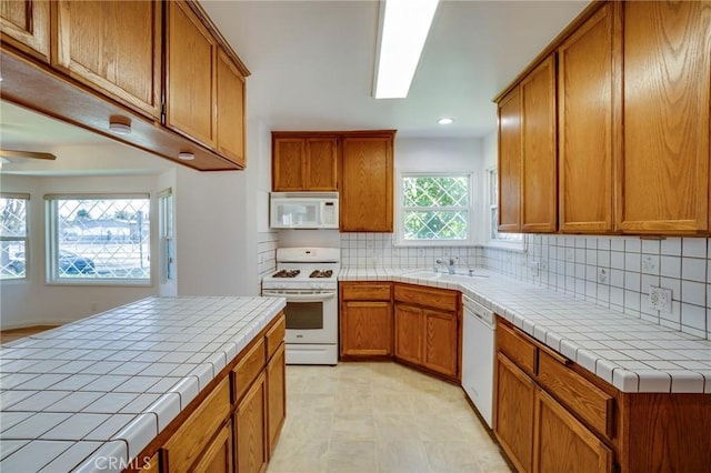 kitchen featuring tile countertops, sink, decorative backsplash, ceiling fan, and white appliances