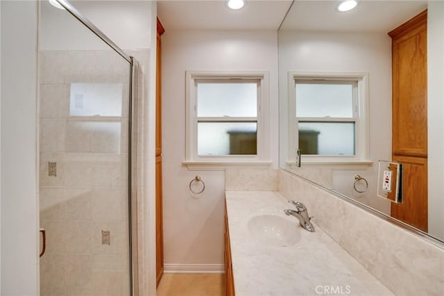 bathroom with vanity, a shower with shower door, and a healthy amount of sunlight