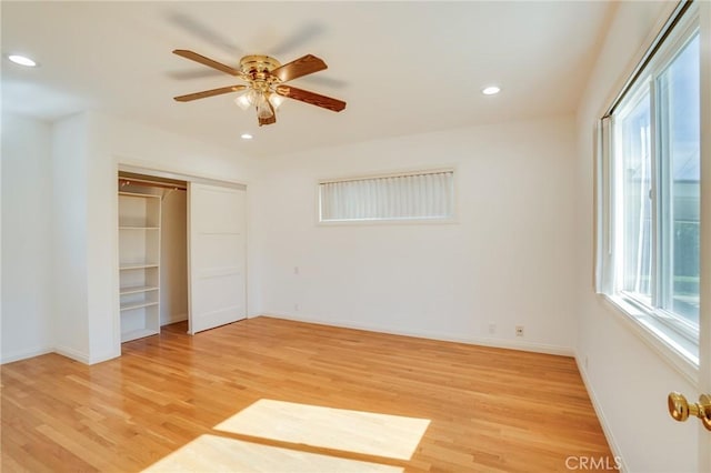 unfurnished bedroom featuring multiple windows, a closet, ceiling fan, and light wood-type flooring