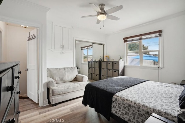 bedroom featuring a closet, ceiling fan, light hardwood / wood-style floors, and multiple windows