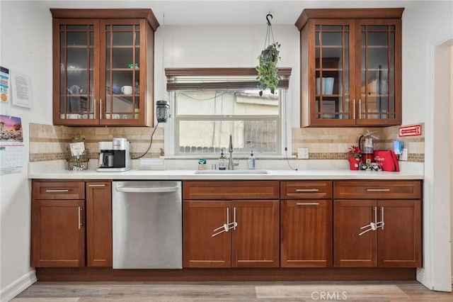 kitchen with dishwasher, sink, light hardwood / wood-style floors, and decorative backsplash