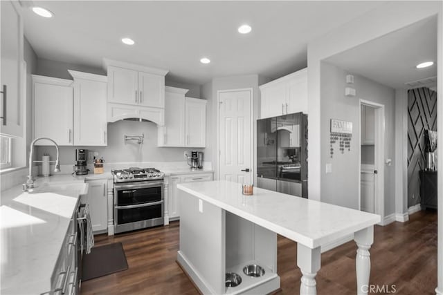 kitchen featuring range with two ovens, freestanding refrigerator, white cabinets, and a sink