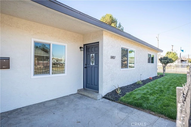 entrance to property with a patio and a lawn