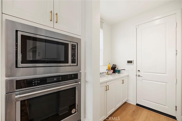 kitchen featuring light hardwood / wood-style floors, white cabinets, and appliances with stainless steel finishes