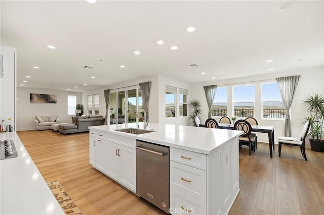 kitchen featuring sink, light wood-type flooring, an island with sink, stainless steel appliances, and white cabinets