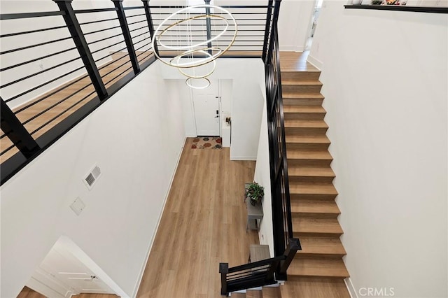 stairway featuring hardwood / wood-style flooring and a chandelier