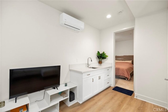 bathroom with sink, hardwood / wood-style floors, and an AC wall unit