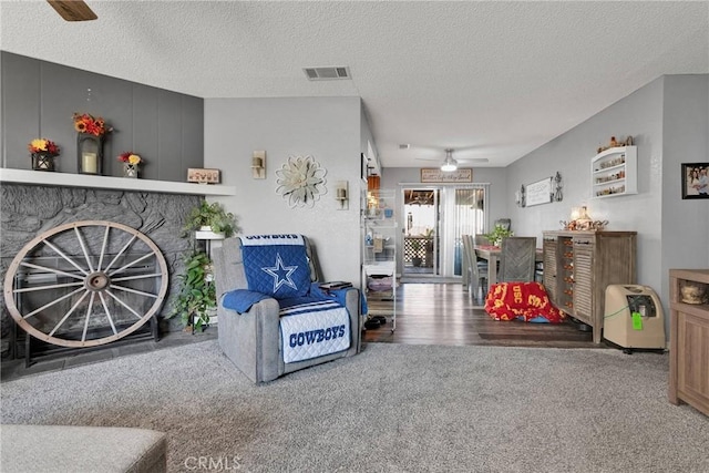 carpeted living room with ceiling fan and a textured ceiling