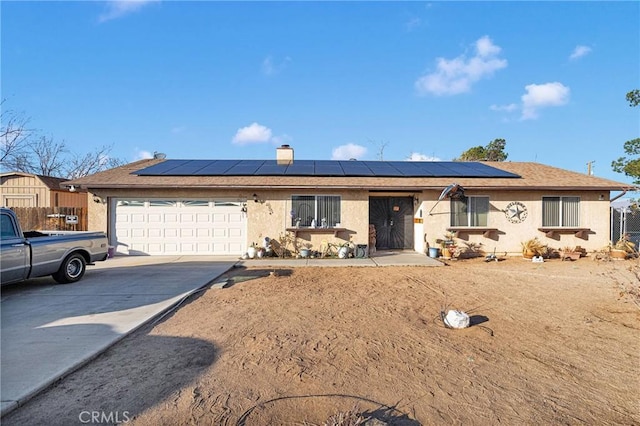 ranch-style home featuring a garage, roof mounted solar panels, concrete driveway, and stucco siding