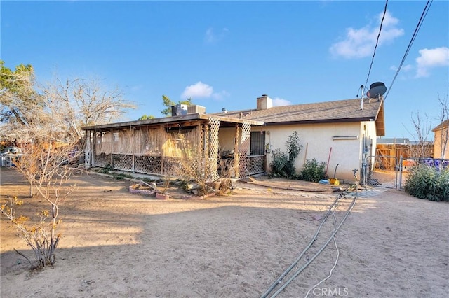 back of property with a gate, fence, and stucco siding