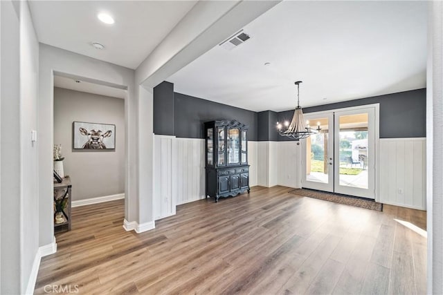 unfurnished dining area with an inviting chandelier and light wood-type flooring