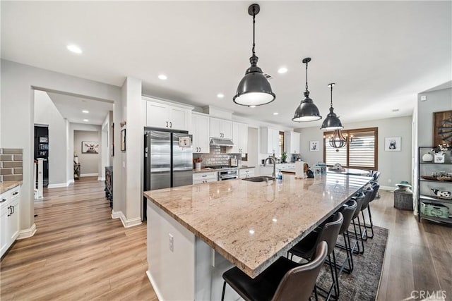 kitchen featuring a large island with sink, range, and white cabinets