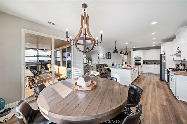 dining room featuring sink, a notable chandelier, and hardwood / wood-style floors