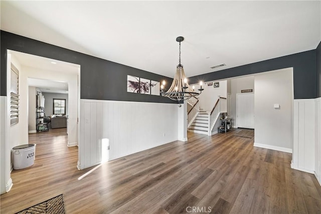 unfurnished dining area with wood-type flooring and a chandelier