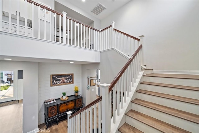 stairway featuring a towering ceiling and hardwood / wood-style floors