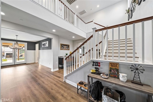 staircase with a chandelier, hardwood / wood-style floors, and a high ceiling