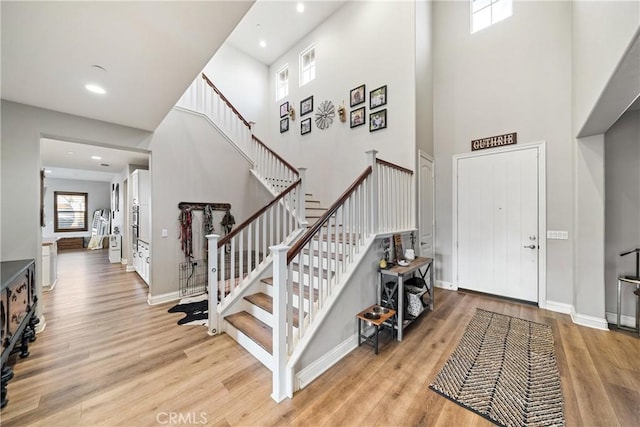 foyer featuring a towering ceiling and light hardwood / wood-style flooring