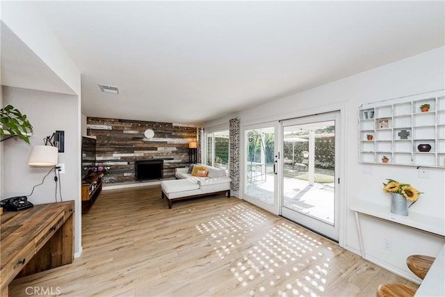 living room with wooden walls, a fireplace, and light wood-type flooring