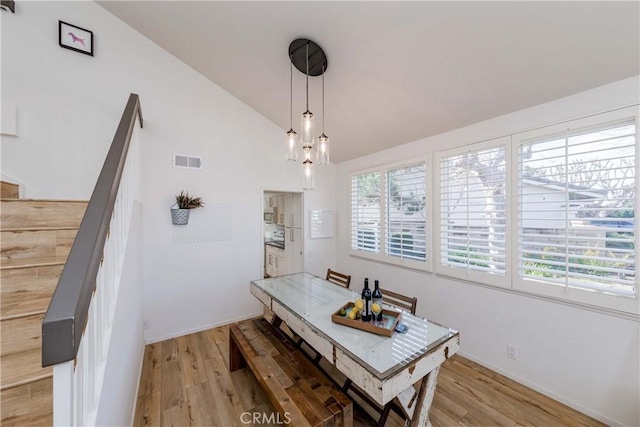 dining room featuring lofted ceiling and light hardwood / wood-style flooring