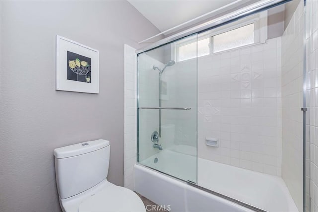 bathroom with toilet and combined bath / shower with glass door