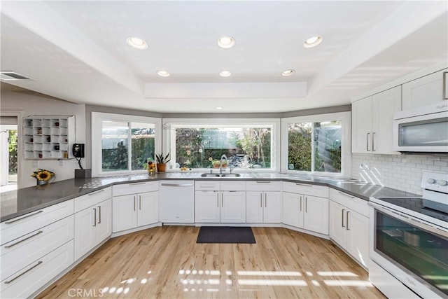 kitchen featuring a raised ceiling, sink, white cabinets, and white appliances