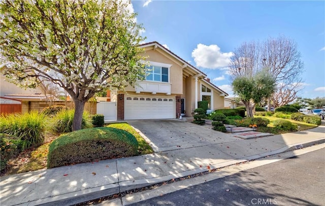 view of front of house featuring concrete driveway, stucco siding, an attached garage, fence, and brick siding