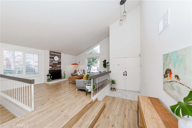 entrance foyer with high vaulted ceiling, a large fireplace, visible vents, and light wood-style flooring