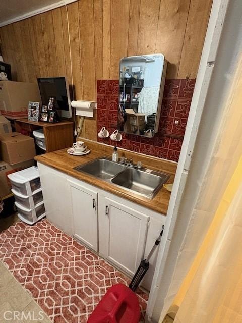 kitchen with sink, white cabinets, and wooden walls