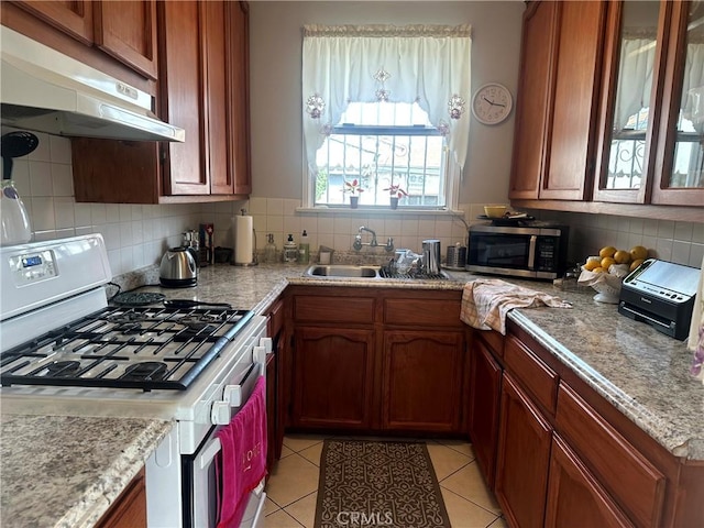 kitchen with light tile patterned floors, decorative backsplash, sink, and white range with gas stovetop