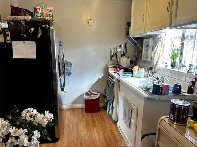 kitchen featuring gas range gas stove, light hardwood / wood-style floors, and stainless steel fridge with ice dispenser