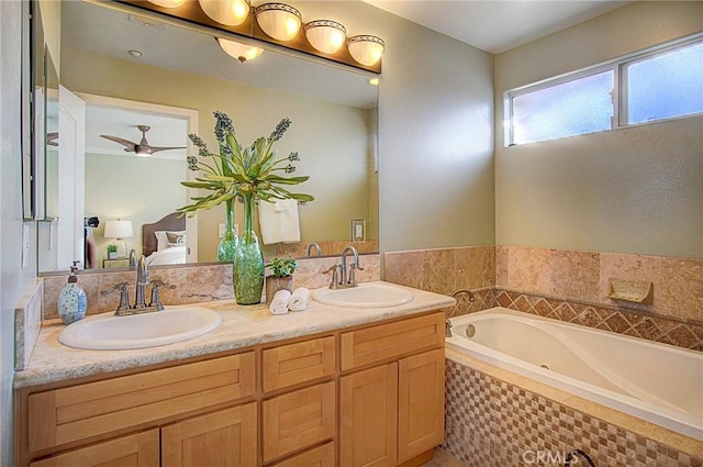 bathroom featuring vanity, a relaxing tiled tub, and ceiling fan