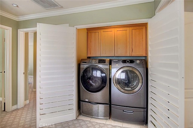 laundry room with ornamental molding, washing machine and dryer, and cabinets